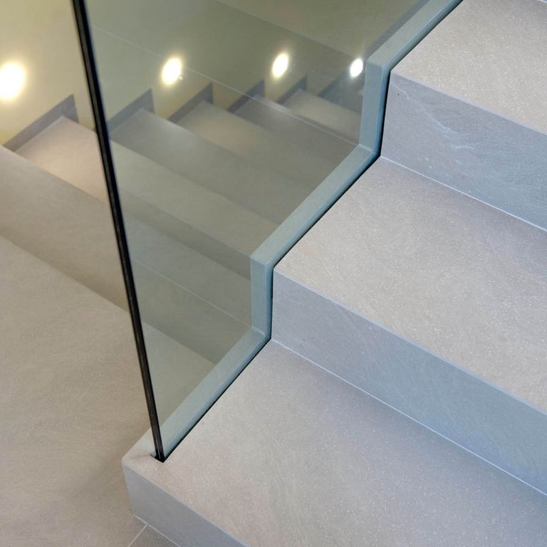 Application image for Giallo Avorio Limestone. The image shows this material being used for interior floor and monolithic steps. The surface finish shown is honed. Dominant colors shown are blue and gray; with a beige secondary.