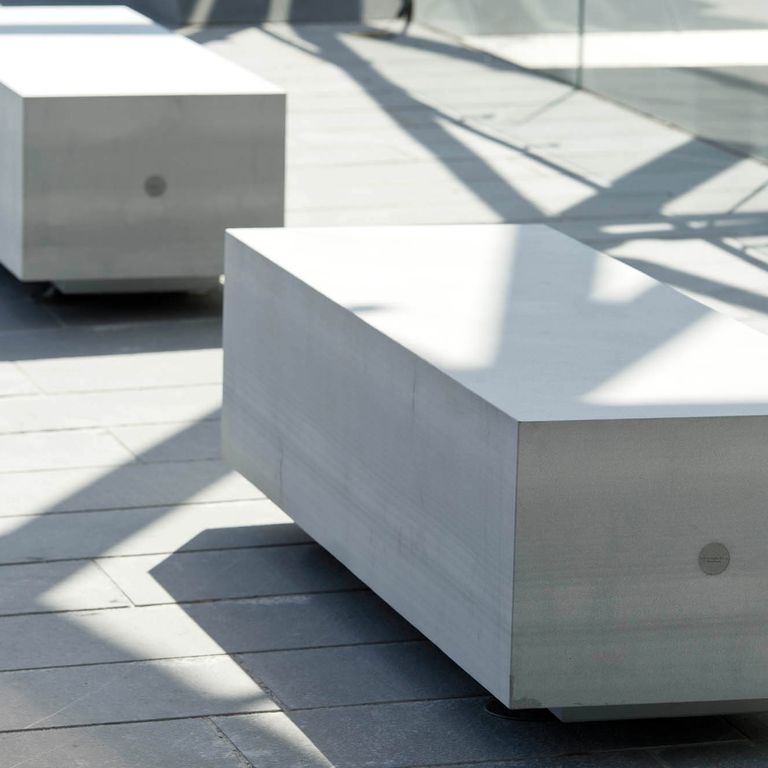 Application image for Pietra Forte Fiorentina Sandstone. The image shows this material being used for seating & benches and interior floor. The surface finish shown is honed. Dominant colors shown are blue, green and gray. The color mix creates a cool feeling. Regular color pattern.