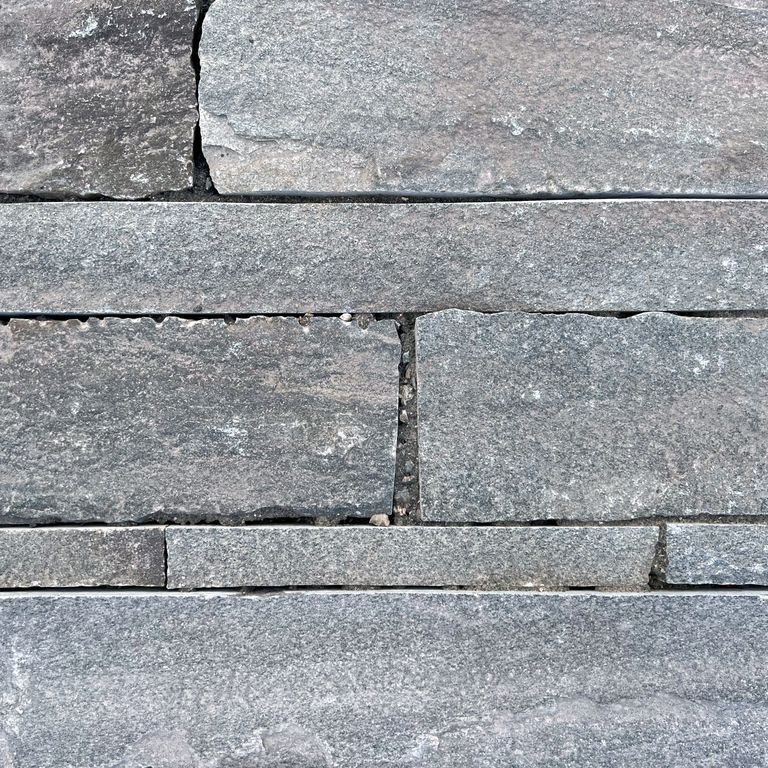Best close-up image for Reclaimed Quartzite Plank Pavers - Blue/Gray. The image shows this material being used in a patio pavers application. The surface finish shown is a combination of split-face with flat plane, weathered and worn. Dominant colors shown are beige, blue, brown and gray; with green, orange/rust, purple, white, tan and cream secondaries. Regular, linear and blotched color patterns. Contains some mica.