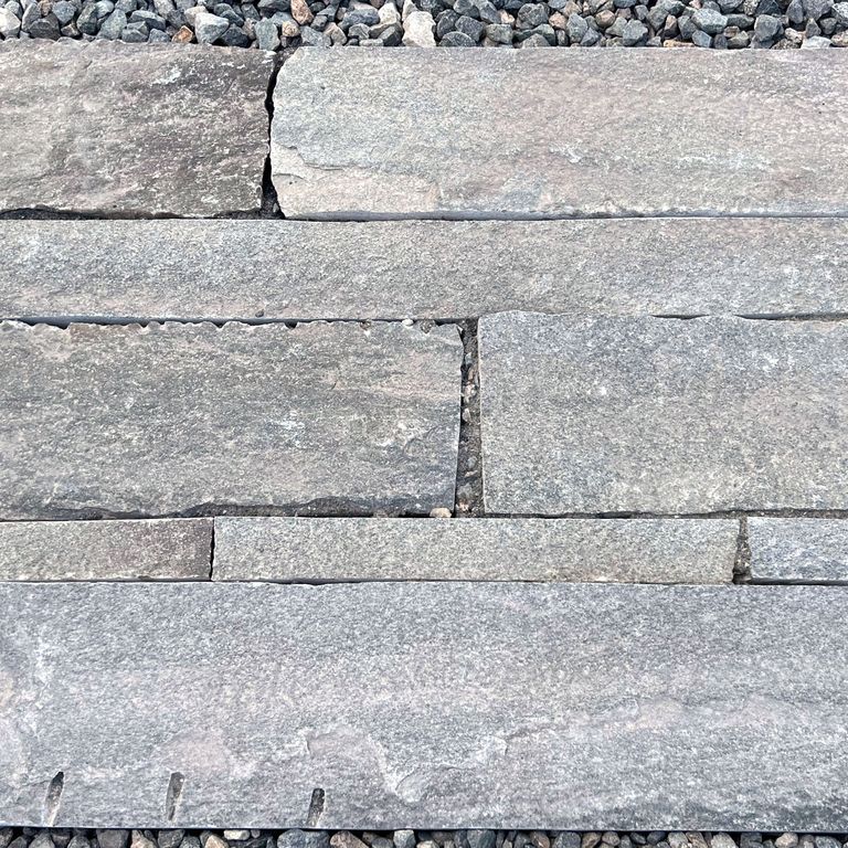 Feature image for Reclaimed Quartzite Plank Pavers - Blue/Gray. The image shows this material being used in a patio pavers application. The surface finish shown is a combination of split-face with flat plane, weathered and worn. Dominant colors shown are blue and gray; with beige, brown, green, orange/rust, pink, purple, white, tan and cream secondaries. Regular, linear, fine speckled and blotched color patterns. Contains some mica.