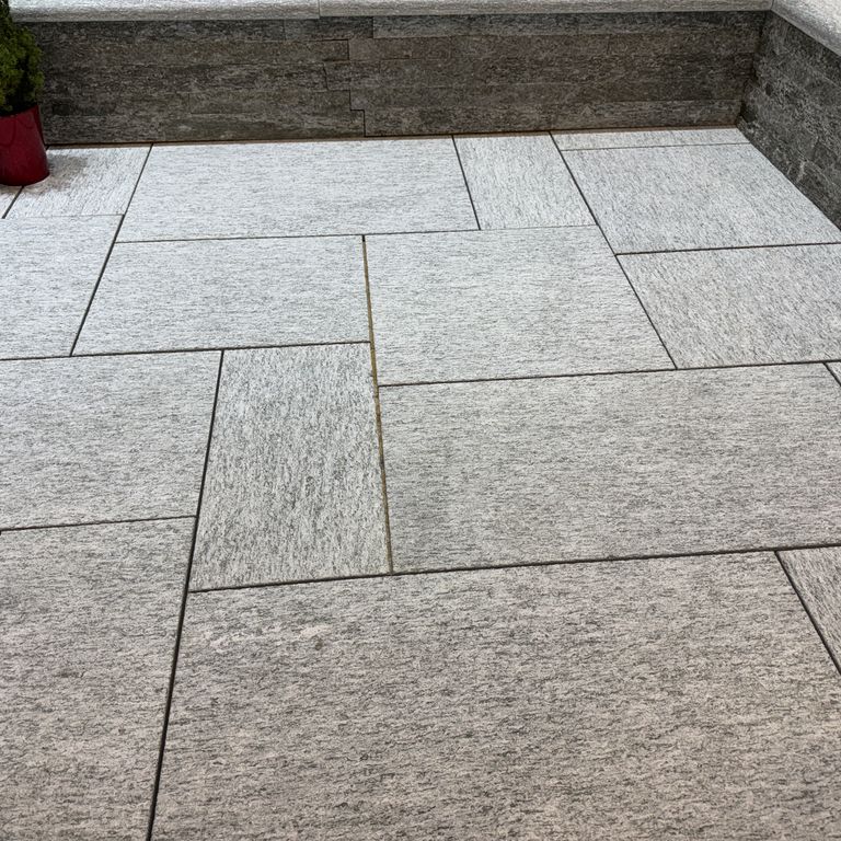 Application image for Pietra Italia Blue/Gray Gneiss. The image shows this material being used in a patio pavers application. The surface finish shown is sand blasted. The dominant color shown is gray. The color mix creates a cool feeling.