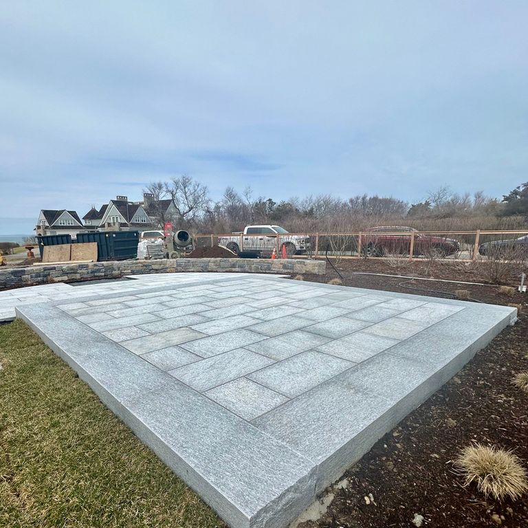 Application image for Pietra Italia Blue/Gray Gneiss. The image shows this material being used in a patio pavers application. The surface finish shown is sand blasted. Dominant colors shown are blue and pink. The color mix creates a cool feeling.