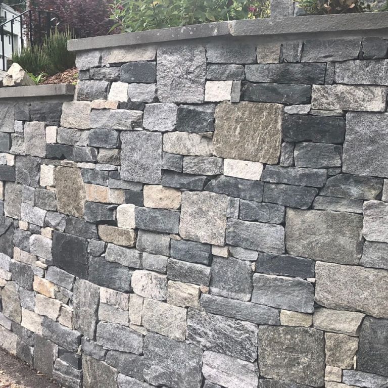 Application image for Granite - Windsor Blend Tin Veneer. The image shows this material being used for thin veneer and retaining wall. The surface finish shown is . The dominant color shown is gray. The color mix creates a warm feeling. Regular, streaked and random color patterns.