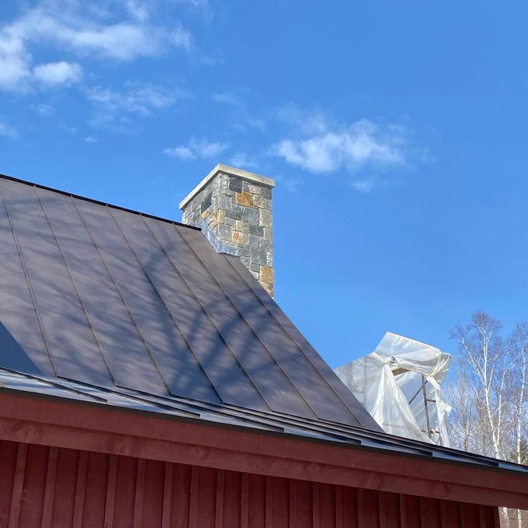 Application image for Granite - Quaker Hill Blend Tin Veneer. The image shows this material being used in a chimney application. The dominant color shown is blue. The color mix creates a cool feeling. Speckled and random color patterns.