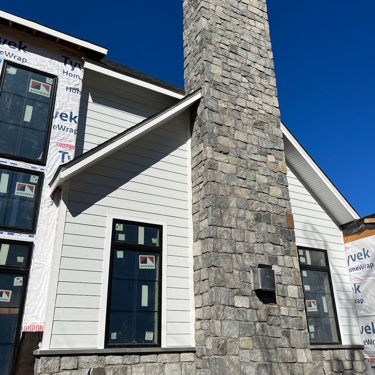 Application image for Granite - Quaker Hill Blend Tin Veneer. The image shows this material being used in a chimney application. Dominant colors shown are blue and gray. The color mix creates a cool feeling. Streaked and speckled color patterns.