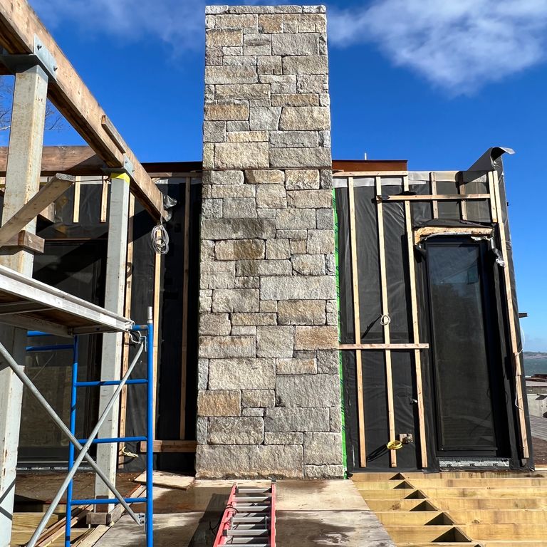 Application image for Granite - Reclaimed Curbstone Blend. The image shows this material being used for full bed veneer and chimney. Dominant colors shown are beige, gray and tan. Speckled, blotched, random and coarse speckled color patterns.