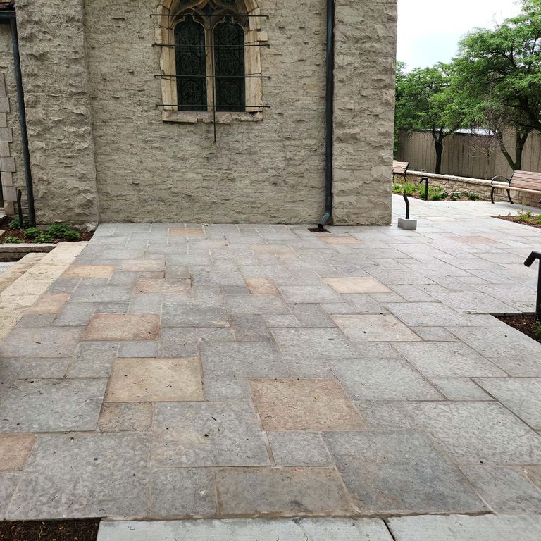 Application image for Limestone - Madison - Full Color. The image shows this material being used for landscape curbing & edging, path pavers and treads. The surface finish shown is flamed. The dominant color shown is gray; with beige, blue, purple, white and cream secondaries. The color mix creates a cool feeling. Regular and cloudy color patterns. Contains mineral inclusions.