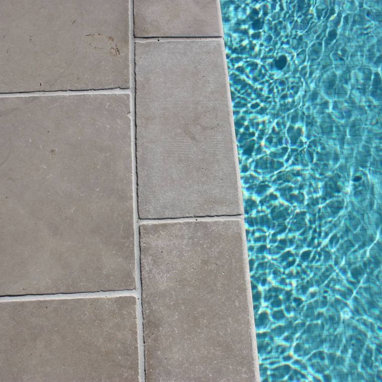Application image for Limestone - Meknes Beige. The image shows this material being used for pool coping and pool deck pavers. The surface finish shown is antiqued. Dominant colors shown are beige, gray and tan. The color mix creates a warm feeling.