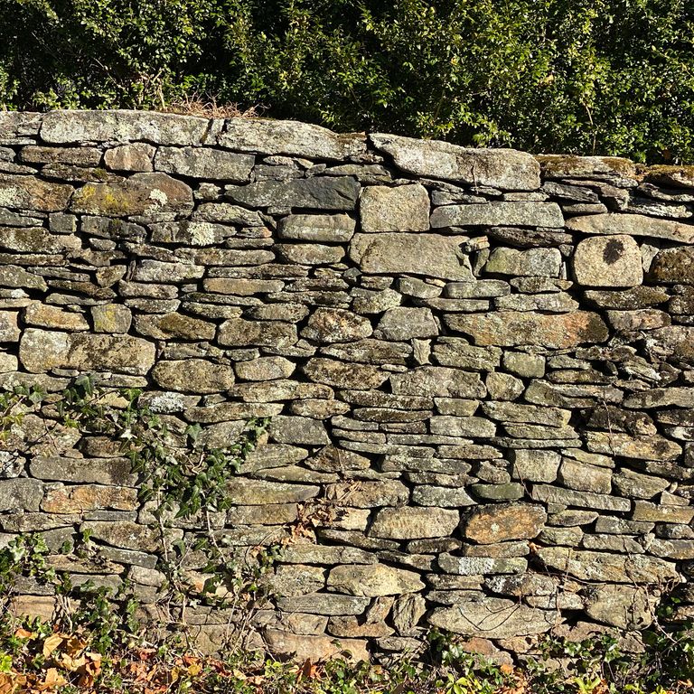Best close-up image for Fieldstone - New England Flats. The image shows this material being used in a landscape wallstone application. The surface finish shown is weathered. Dominant colors shown are beige, brown and tan; with gray, orange/rust and cream secondaries. Exhibits 