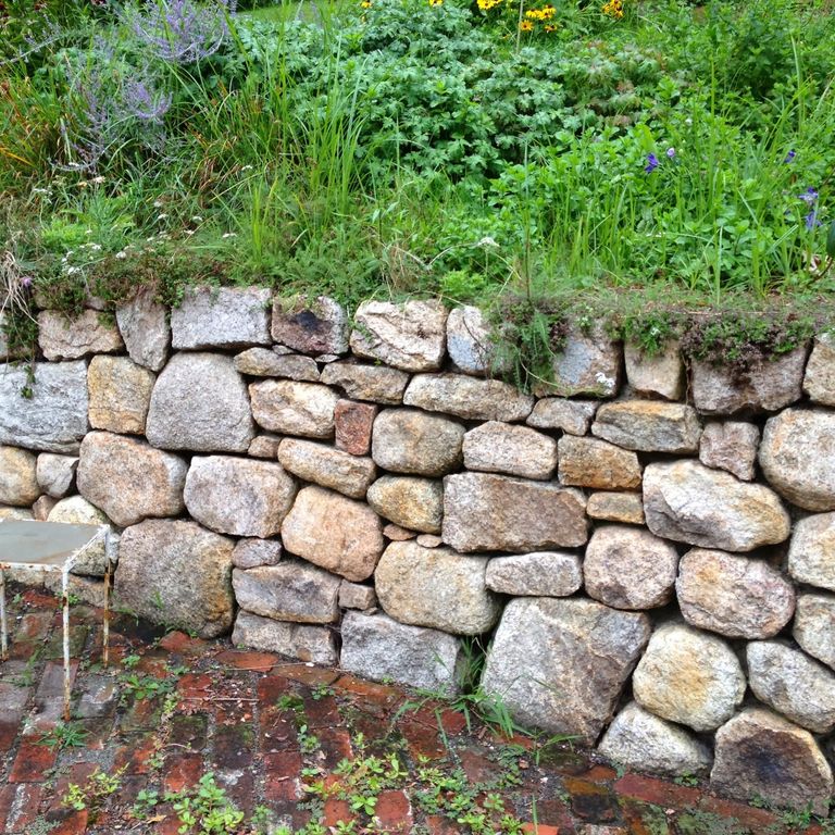 Application image for Fieldstone - New England Mix. The image shows this material being used in a landscape wallstone application. The surface finish shown is weathered. The dominant color shown is gray.
