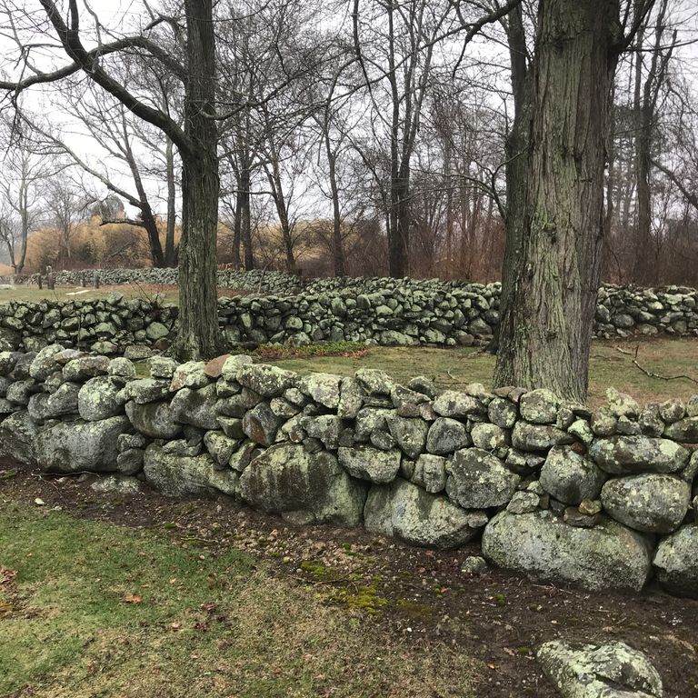 Application image for Fieldstone - New England Mix. The image shows this material being used in a landscape wallstone application. The surface finish shown is weathered. The dominant color shown is gray. The color mix creates a cool feeling.