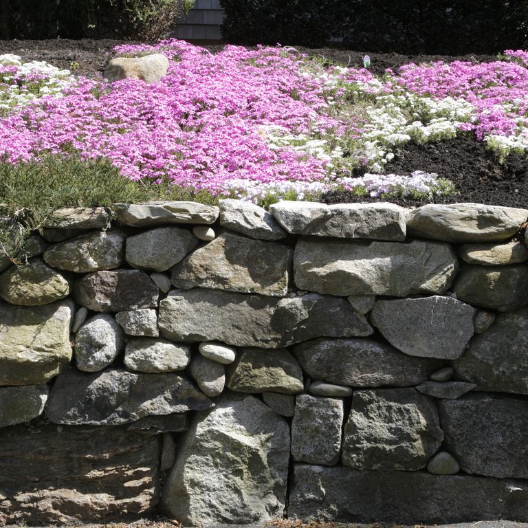 Application image for New England Fieldstone Mix. The image shows this material being used in a landscape wallstone application. The surface finish shown is weathered. The dominant color shown is gray. The color mix creates a warm feeling.