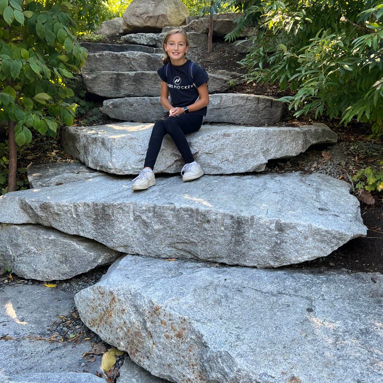 Application image for Reclaimed New England Granite Quarry Tailings. The image shows this material being used in a monolithic steps application. Dominant colors shown are blue and gray. The color mix creates a cool feeling. Speckled color pattern.