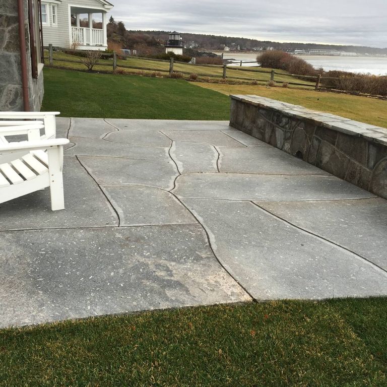 Application image for Oak Mountain Granite. The image shows this material being used in a patio pavers application. The surface finish shown is flamed. Dominant colors shown are brown and gray; with black, white and tan secondaries. The color mix creates a warm feeling. Regular and random color patterns. Contains mineral inclusions.