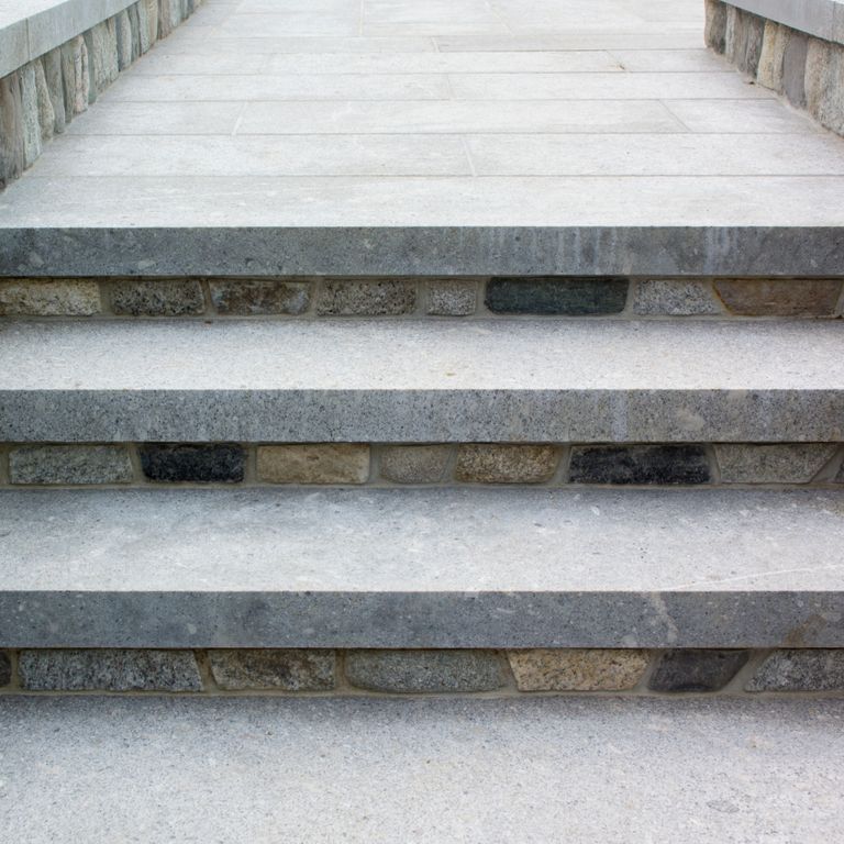 Application image for Granite - Oak Mountain. The image shows this material being used in a treads application. The surface finish shown is flamed. The dominant color shown is gray; with blue, brown and white secondaries. The color mix creates a cool feeling. Solid color pattern. Contains mineral inclusions.
