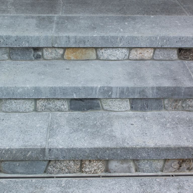 Application image for Oak Mountain Granite. The image shows this material being used in a treads application. The surface finish shown is flamed. Dominant colors shown are blue and gray. The color mix creates a cool feeling. Regular color pattern. Contains mineral inclusions.