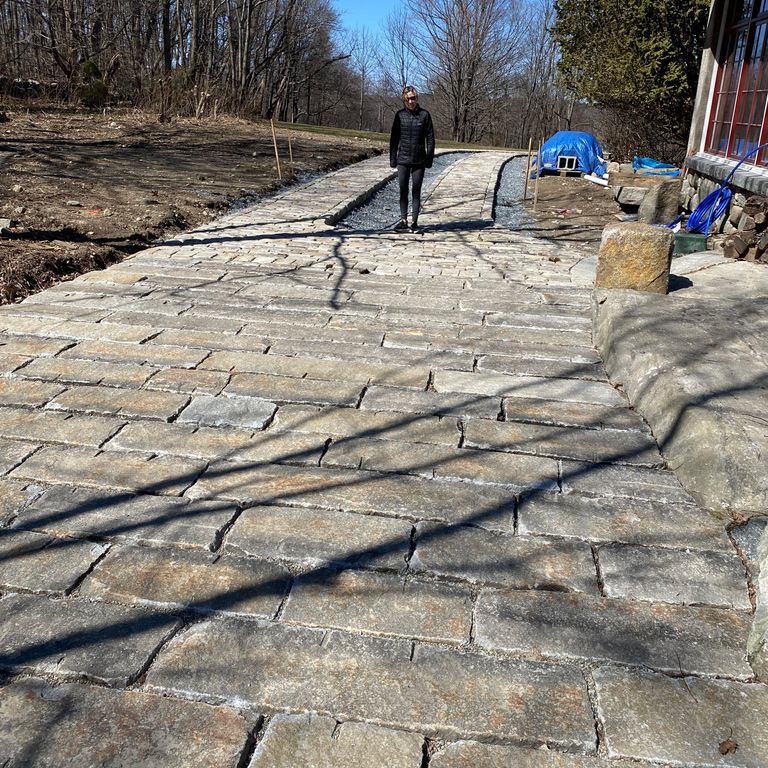 The image shows this material being used in a driveway pavers application.
