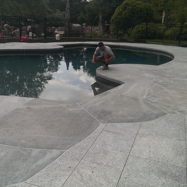 Application image for Mystic Mountain - Worked Surface. The image shows this material being used for pool coping, patio pavers and pool deck pavers. The surface finish shown is flamed. The dominant color shown is gray. Exhibits 