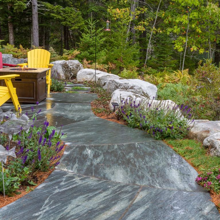 Application image for Mystic Mountain - Worked Surface. The image shows this material being used for path pavers and patio pavers. The surface finish shown is flamed. Dominant colors shown are blue and gray. The color mix creates a cool feeling. Streaked color pattern.