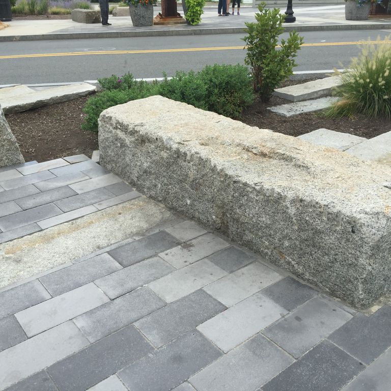 Application image for Reclaimed Granite Bridge Blocks. The image shows this material being used in a seating & benches application. The surface finish shown is a combination of weathered and worn. The dominant color shown is gray; with a tan secondary. The color mix creates a warm feeling.