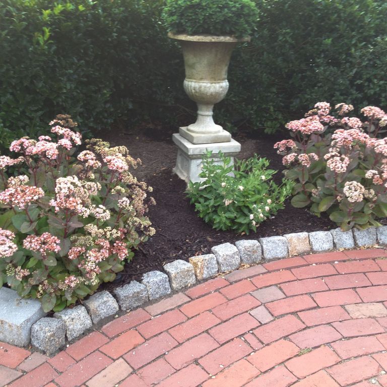Application image for Reclaimed New England Granite Cobblestones - Medium. The image shows this material being used in a landscape curbing & edging application. This is a landscape stone for outdoor commercial and residential applications. Suitable for general use, freeze-thaw conditions, low heat absorption surfaces, high traffic areas and low slipperiness surfaces situations. Moderate to higher on the price spectrum.