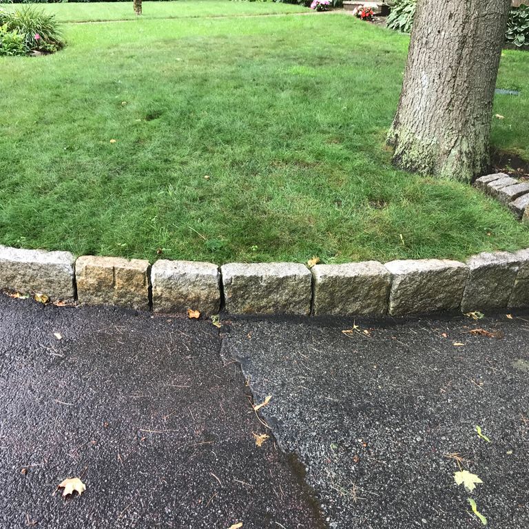 Application image for Reclaimed New England Granite Cobblestones - Super Jumbo. The image shows this material being used in a landscape curbing & edging application. This is a landscape stone for outdoor commercial and residential applications. Suitable for general use, freeze-thaw conditions, low heat absorption surfaces, high traffic areas and low slipperiness surfaces situations. Moderate to higher on the price spectrum.