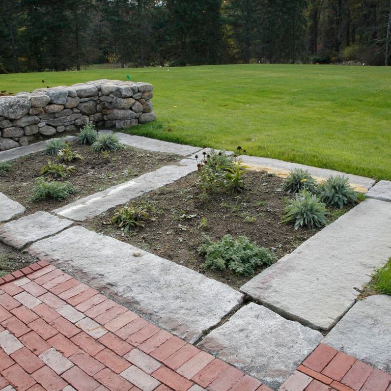 Application image for Reclaimed Granite Foundation Stone. The image shows this material being used in a landscape curbing & edging application. This is a building and landscape stone for outdoor commercial and residential applications. Suitable for general use, freeze-thaw conditions, low heat absorption surfaces, high traffic areas and low slipperiness surfaces situations. Higher to high on the price spectrum.