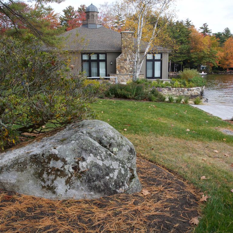 Application image for New England Fieldstone Boulders & Ledgestone. The image shows this material being used in a landscape boulders & ledge application. The surface finish shown is weathered. The dominant color shown is gray. The color mix creates a cool feeling.