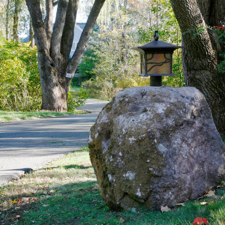 Application image for New England Fieldstone Boulders & Ledgestone. The image shows this material being used for garden accents and landscape boulders & ledge. The surface finish shown is weathered. The dominant color shown is gray. The color mix creates a cool feeling.