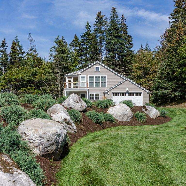 Application image for New England Fieldstone Boulders & Ledgestone. The image shows this material being used in a landscape boulders & ledge application. The surface finish shown is weathered. The dominant color shown is gray.