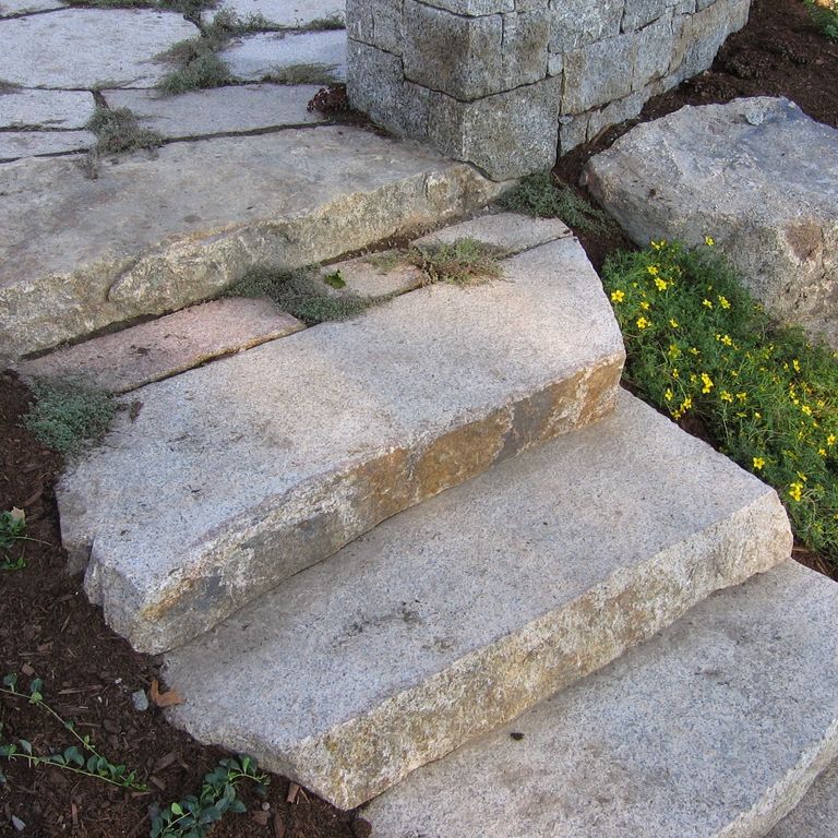 Application image for New England Fieldstone Boulders & Ledgestone. The image shows this material being used for landings and treads. The surface finish shown is weathered. The dominant color shown is gray. The color mix creates a cool feeling.