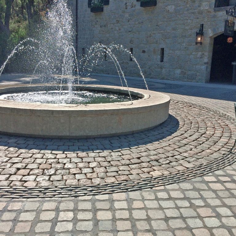 Application image for Reclaimed European Porphyry Cobblestones. The image shows this material being used in a public area application. The surface finish shown is . The dominant color shown is gray. The color mix creates a cool feeling.