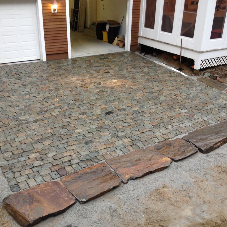 Application image for Reclaimed European Porphyry Cobblestones. The image shows this material being used in a driveway pavers application. The surface finish shown is . The dominant color shown is gray. The color mix creates a warm feeling.