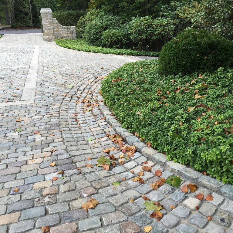 Feature image for Reclaimed European Sandstone Cobblestones. The image shows this material being used in a driveway pavers application. The surface finish shown is . The dominant color shown is gray; with beige, blue, brown, orange/rust, purple, white and cream secondaries. Regular, fine speckled and speckled color patterns.