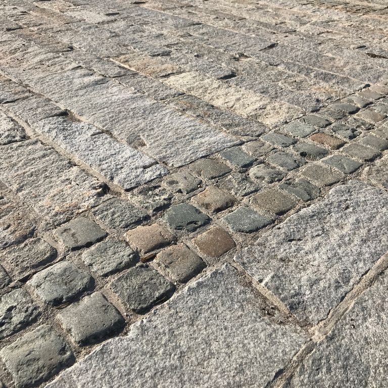 Application image for Reclaimed European Sandstone Cobblestones. The image shows this material being used in a driveway pavers application. The surface finish shown is . The dominant color shown is gray. The color mix creates a warm feeling.