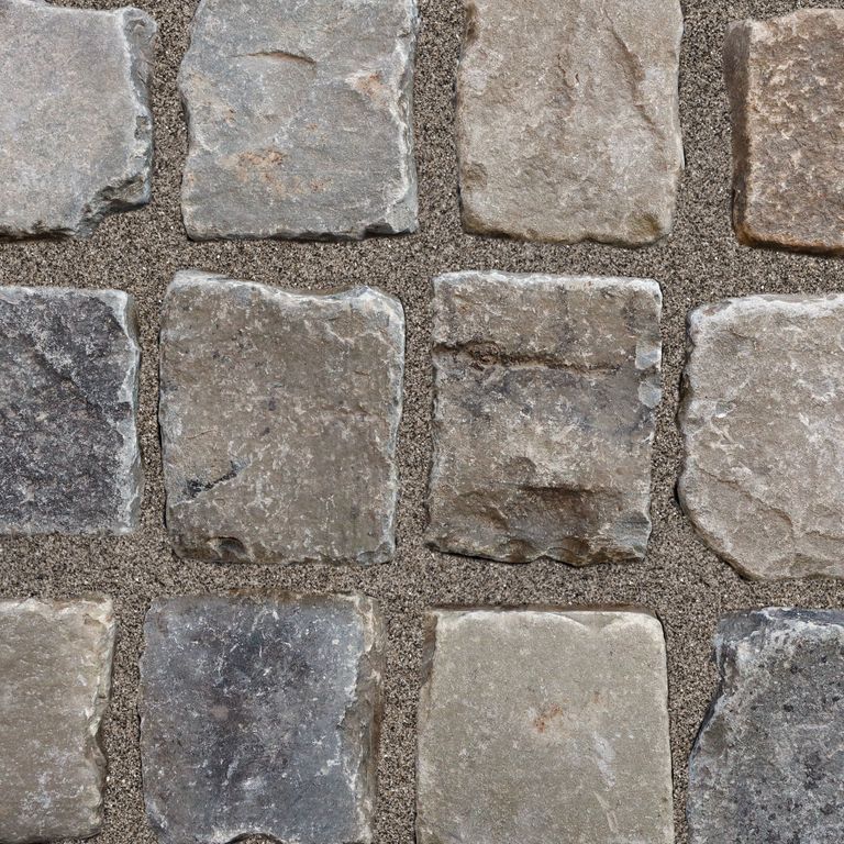 Application image for Reclaimed European Sandstone Cobblestones. The image shows this material being used for driveway pavers, path pavers and patio pavers. The surface finish shown is . The dominant color shown is gray; with beige, black, brown, green, orange/rust, purple, white and tan secondaries. The color mix creates a warm feeling. Regular color pattern.