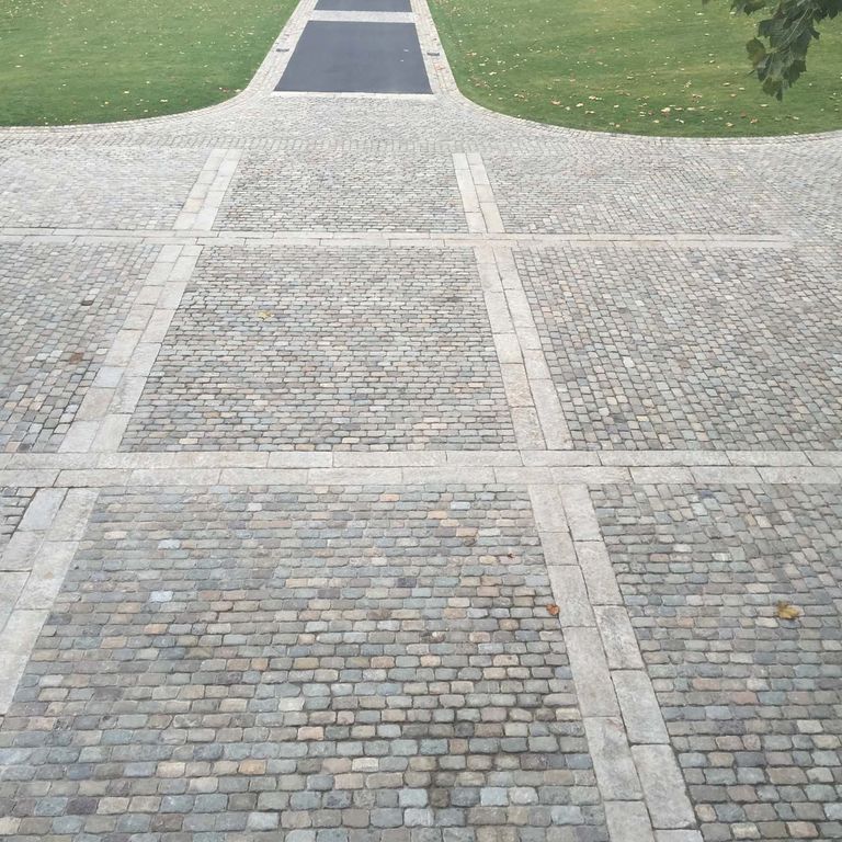 Application image for Reclaimed European Sandstone Cobblestones. The image shows this material being used in a driveway pavers application. The surface finish shown is . The dominant color shown is gray. The color mix creates a warm feeling.