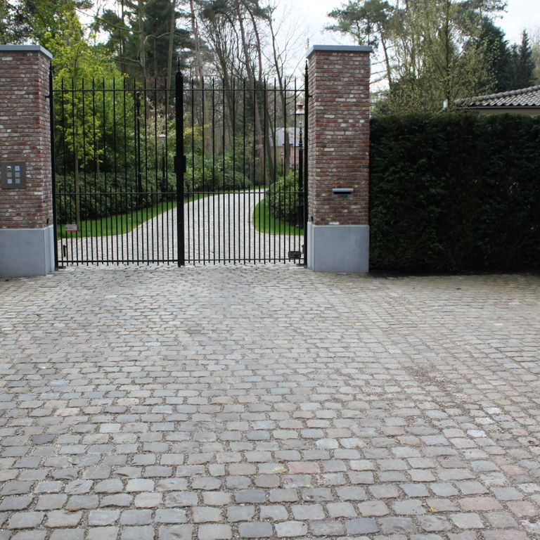 Application image for Reclaimed European Sandstone Cobblestones. The image shows this material being used in a driveway pavers application. The surface finish shown is . The dominant color shown is gray. The color mix creates a warm feeling.