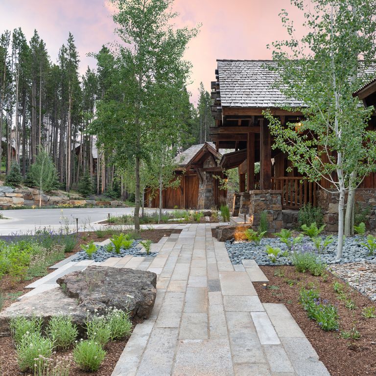 Feature image for Reclaimed Footworn Granite Planks. The image shows this material being used in a path pavers application. The surface finish shown is a combination of weathered and worn. The dominant color shown is gray; with brown, orange/rust and tan secondaries. Speckled and random color patterns.