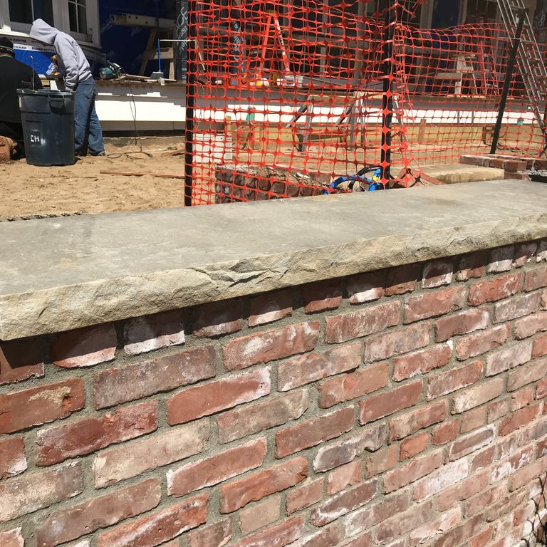 Application image for Reclaimed Sandstone Sidewalk Stones. The image shows this material being used in a wallstone cap application. This is a landscape stone for outdoor commercial and residential applications. Suitable for general use, freeze-thaw conditions, low heat absorption surfaces, high traffic areas, low slipperiness surfaces and high heel compatibilty situations.