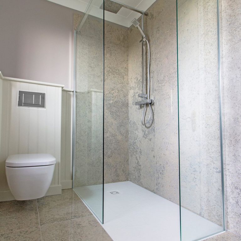 Feature image for Mountain Hard Blue Limestone. The image shows this material being used for interior floor and bath tub & shower. The surface finish shown is polished. The dominant color shown is gray. The color mix creates a cool feeling. Blotched color pattern.