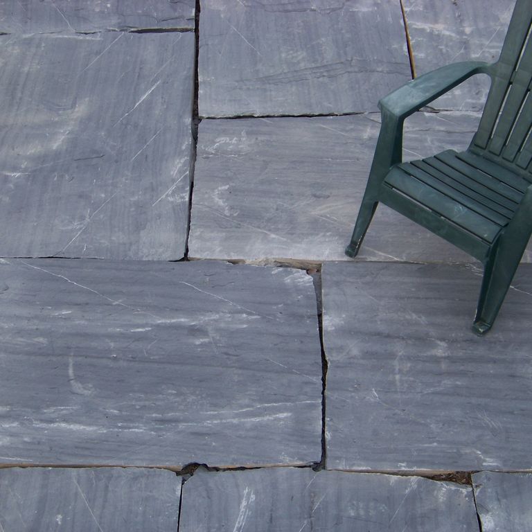 The image shows this material being used in a patio pavers application. Dominant colors shown are blue and gray; with black and white secondaries. Exhibits 