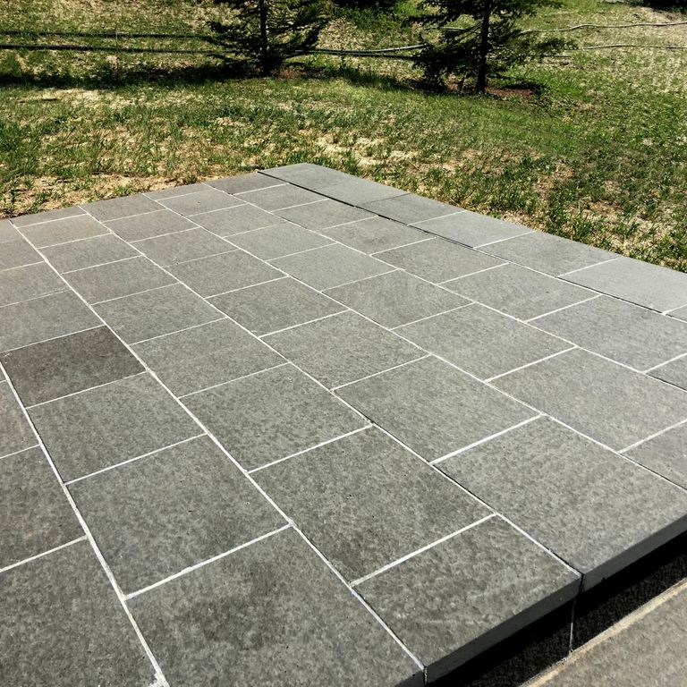 Application image for Nordic Black Basalt. The image shows this material being used in a patio pavers application. The surface finish shown is flamed. The dominant color shown is gray. The color mix creates a warm feeling. Regular color pattern.