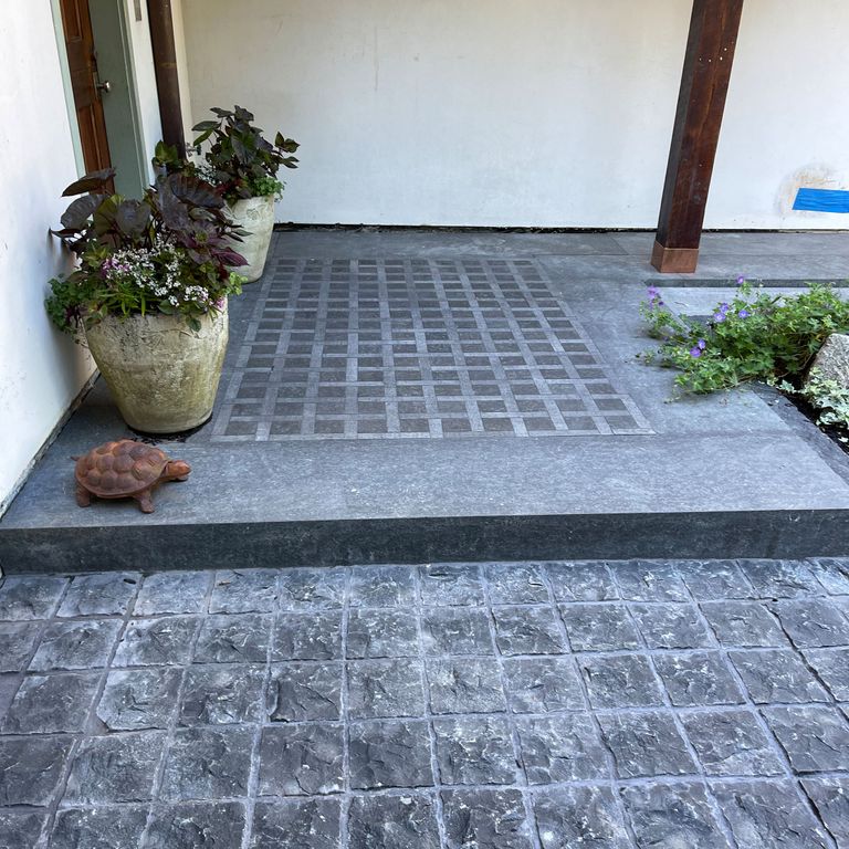Application image for Basalt - Nordic Black. The image shows this material being used in a landings application. The surface finish shown is a combination of adze, flamed and split-face. The dominant color shown is gray. The color mix creates a cool feeling. Solid color pattern.