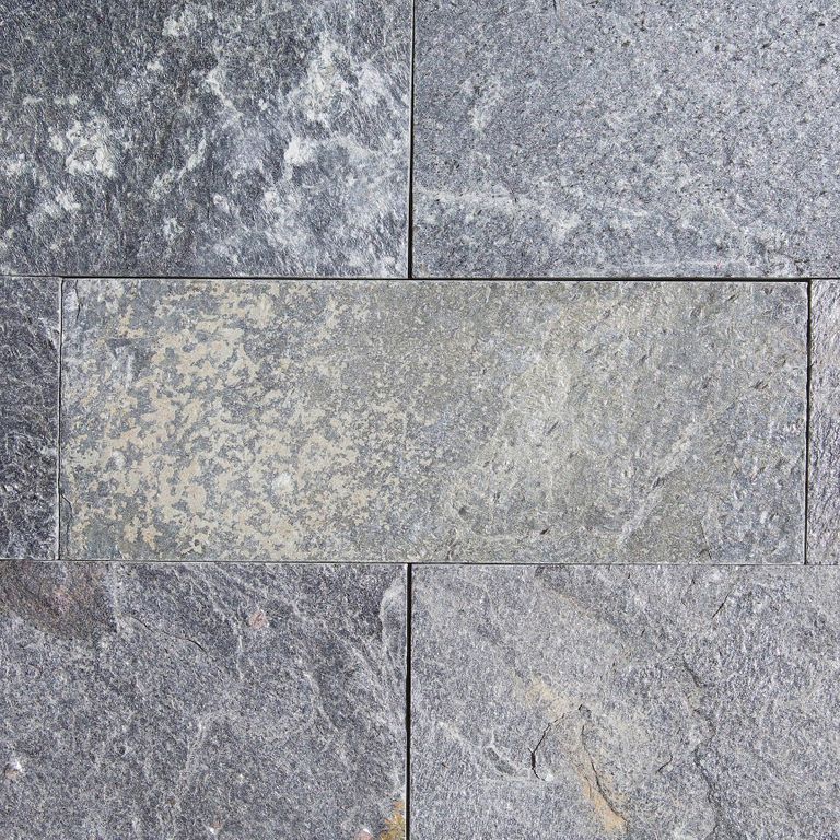 Best close-up image for Quartzite - Amazon. The surface finish shown is split-face with flat plane. The dominant color shown is gray; with blue, brown, green, purple and white secondaries. Exhibits 