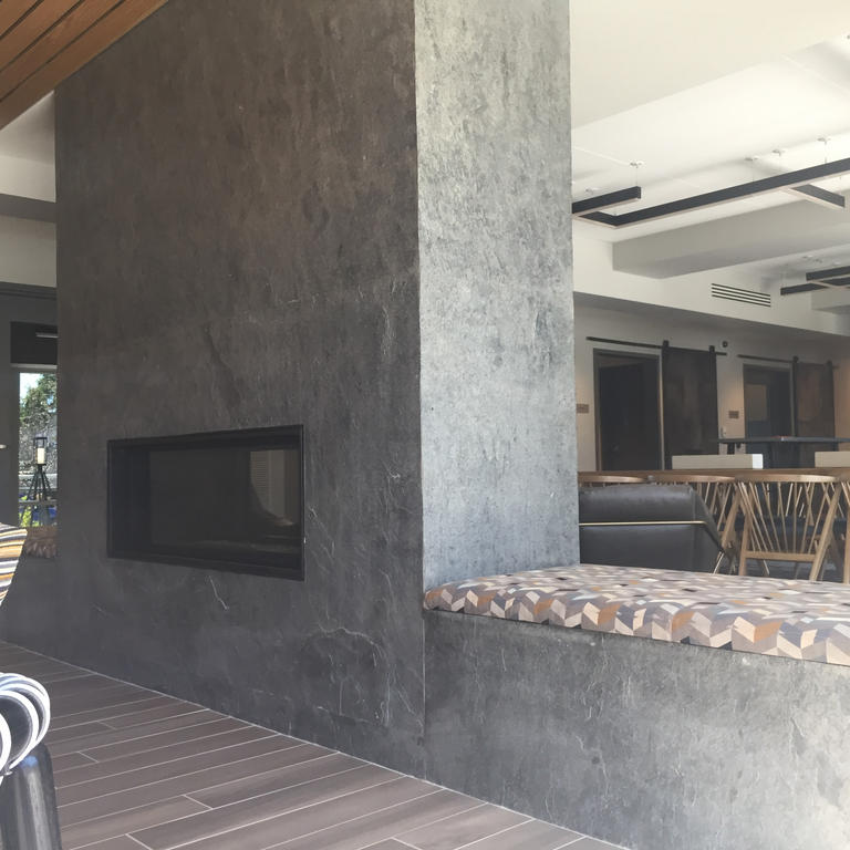 Feature image for Quartzite - Amazon. The image shows this material being used in a fireplace surround application. The dominant color shown is gray; with beige and white secondaries. Exhibits 