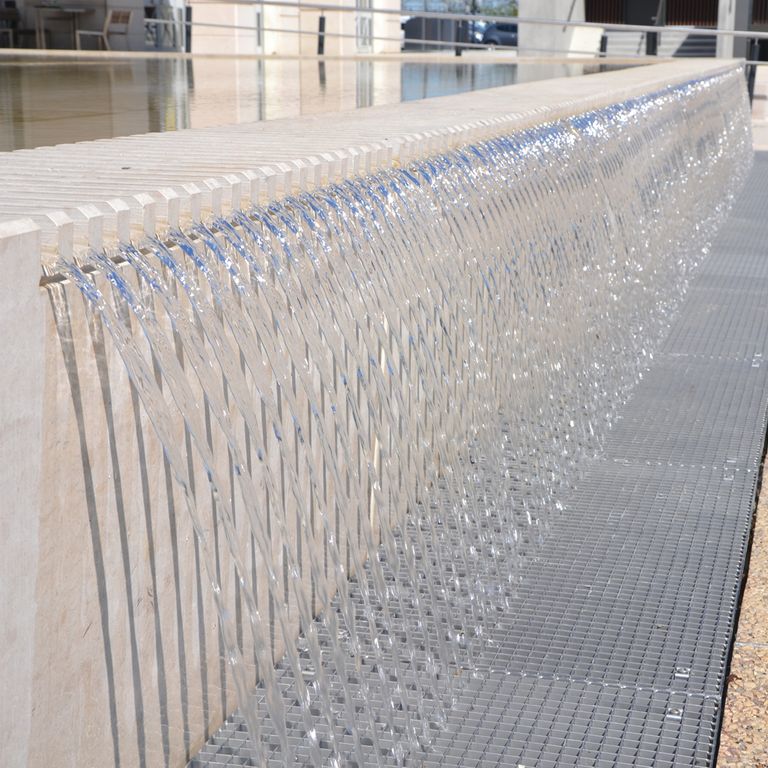 Application image for Classimo Beige Limestone. The image shows this material being used in a water features application. The surface finish shown is honed. Dominant colors shown are beige, gray and purple; with a cream secondary. The color mix creates a warm feeling. Regular and cloudy color patterns.