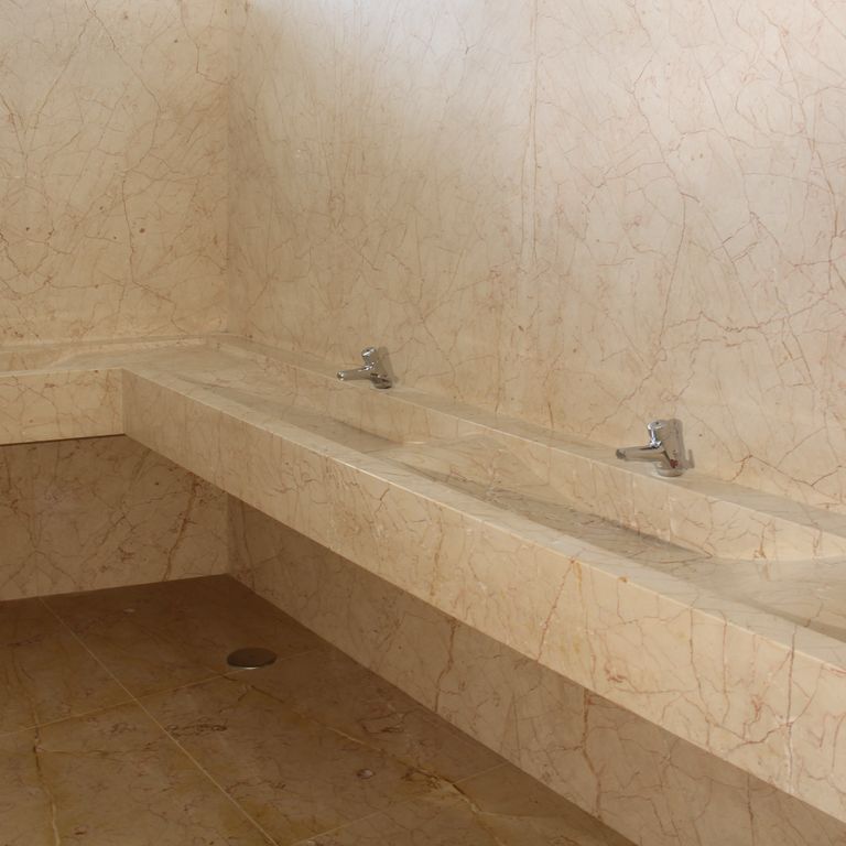 Feature image for Limestone - Portuguese Alpine. The image shows this material being used for interior floor, sinks and thin veneer. Dominant colors shown are beige, tan and cream; with an orange/rust secondary. Exhibits 