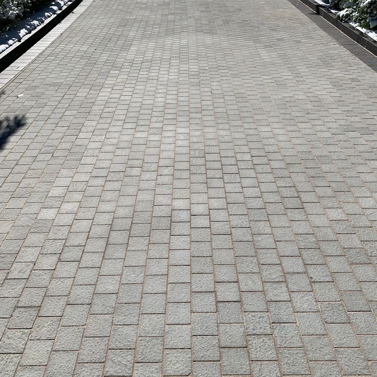 Feature image for Italian Bluestone. The image shows this material being used in a driveway pavers application. The dominant color shown is gray; with green and purple secondaries. The color mix creates a cool feeling. Regular and fine speckled color patterns.