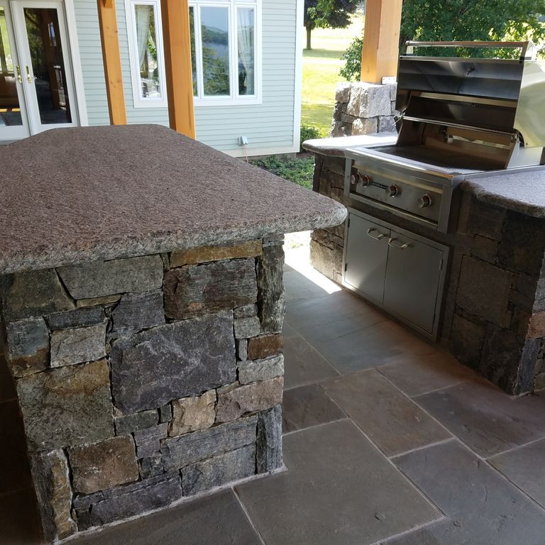 Feature image for Dolph Pond Granite. The image shows this material being used in a thin veneer application. The dominant color shown is gray; with blue, brown, green, orange/rust, purple, white and tan secondaries. The color mix creates a warm feeling.
